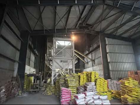 Batching plant tower inside an industrial shed with cement bags stacked on the floor